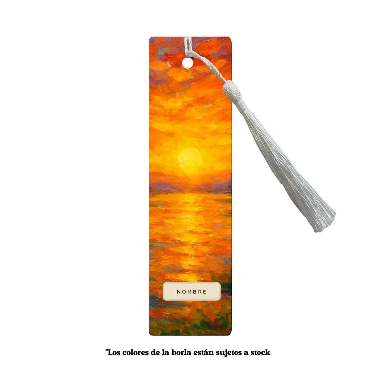 Marcapáginas metálico con borla blanca y diseño Atardecer en tonos cálidos naranjas y dorados.