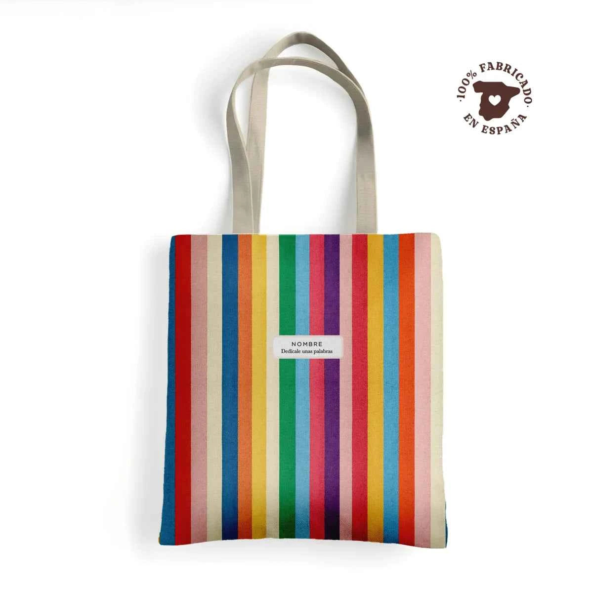 Tote bag de loneta fabricada 100% en España con estampado de rayas multicolor Carnivale, personalizable con nombre y frase.